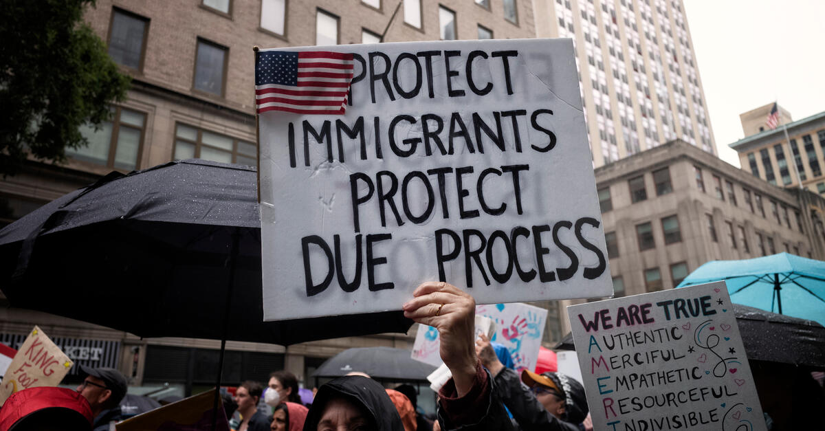 A protester holds a sign that says Protect Immigrants Protect Due Process.