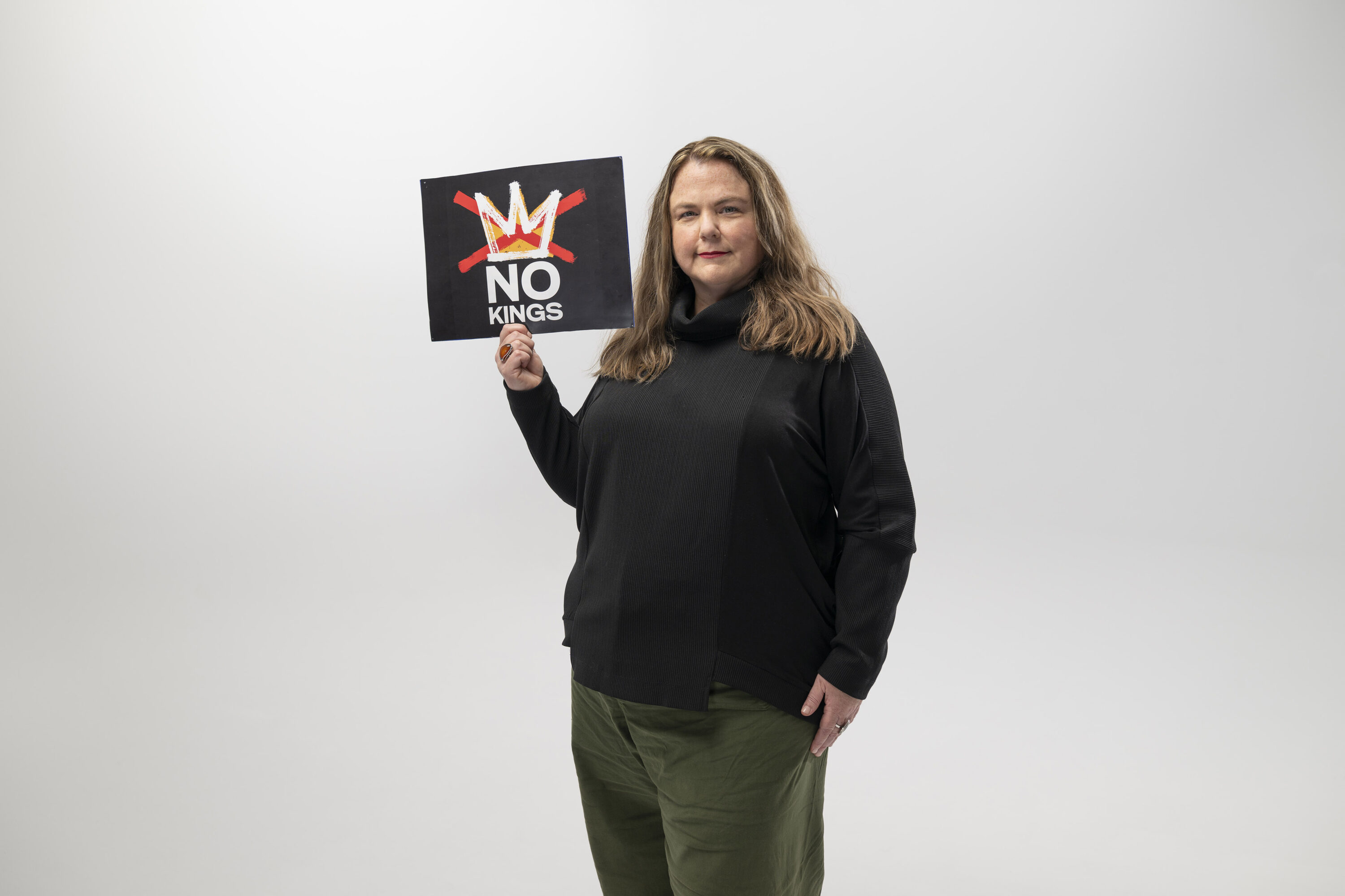 Suzanne Potts holds a sign that says No Kings