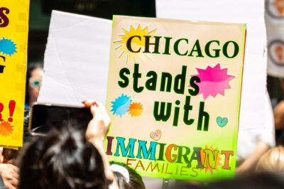 A demonstrator holds a sign that reads "Chicago Stands With Immigrant Families".