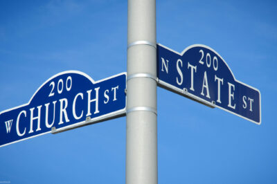 Two street signs at an intersection on a pole reading Church St on one and State St on the other.