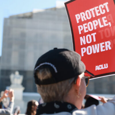 An individual holding a sign that says "Protect People, Not Power" outside of the U.S. Supreme Court ahead of arguments in the Voting Rights case Callais v. Landry.