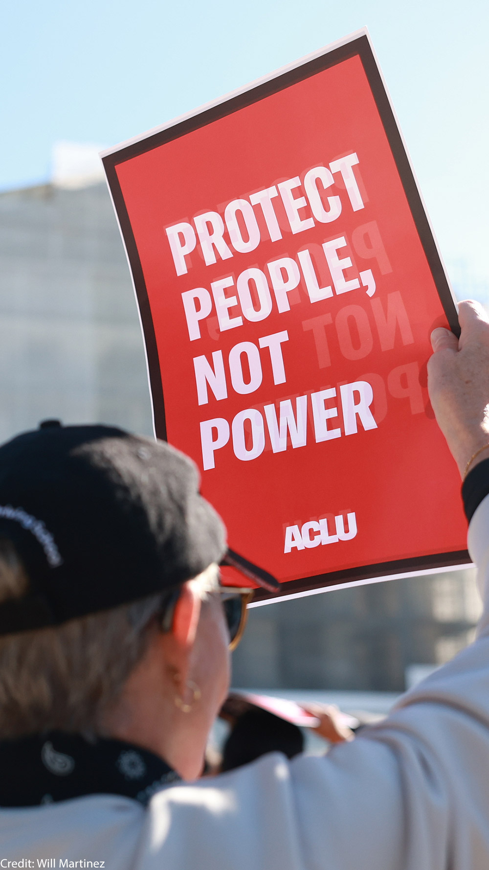 An individual holding a sign that says "Protect People, Not Power" outside of the U.S. Supreme Court ahead of arguments in the Voting Rights case Callais v. Landry.