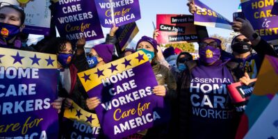 Multiple demonstrators hold up signs that read" "HOME CARE WORKERS CARE FOR AMERICA".