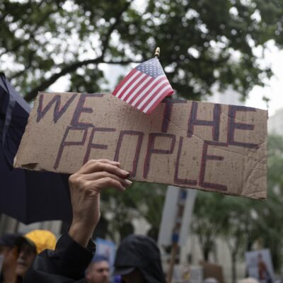 A protester holds up a sign that says "WE THE PEOPLE"