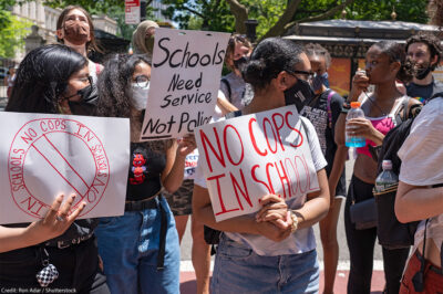 Demonstrators holding signs that read "No Cops In Schools" and "Schools Need Service Not Police" protest outside City Hall in New York City.