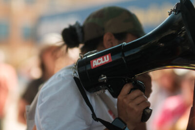 A demonstrator holding a megaphone with an ACLU sticker.