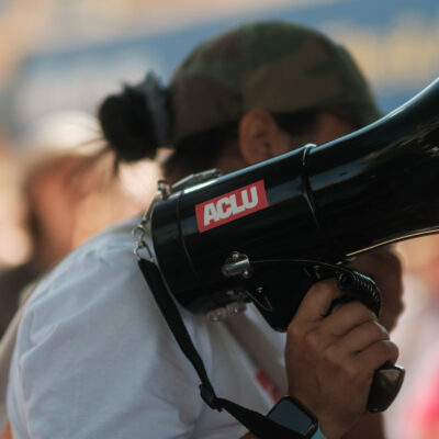 A demonstrator holding a megaphone with an ACLU sticker.