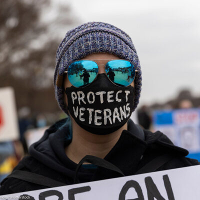 A demonstrator wears a mask with the text ''Protect Veterans'' during the ''Veterans March'' at the National Mall in Washington.