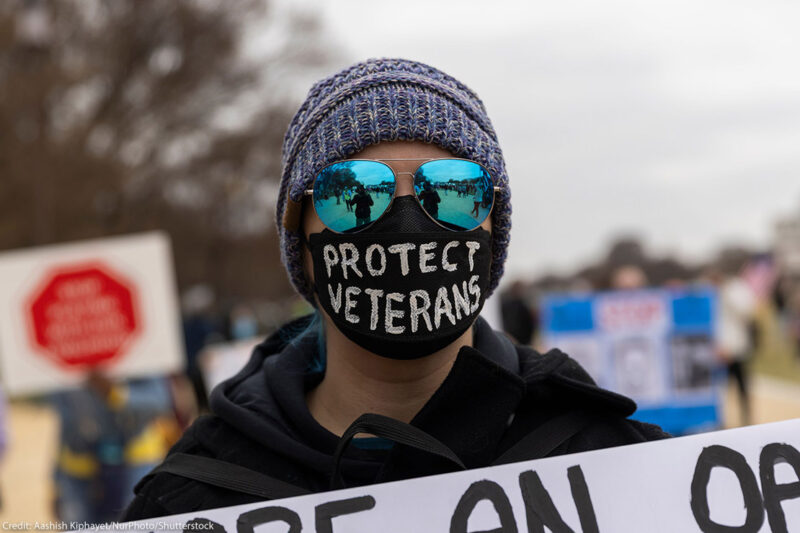 A demonstrator wears a mask with the text ''Protect Veterans'' during the ''Veterans March'' at the National Mall in Washington.