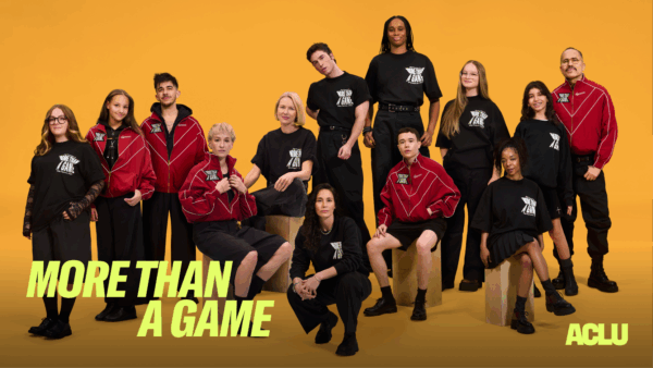A group of athletes, students, and advocates gathered in front of an orange backdrop wearing "More Than A Game" Apparel